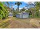 Detached blue garage featuring a large single-car garage door and surrounded by mature trees at 906 W Henry Ave, Tampa, FL 33604