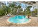 A beautiful inground kidney-shaped pool surrounded by a brick patio, lounge chairs, lush landscaping, and grilling area at 906 W Henry Ave, Tampa, FL 33604