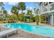 A lovely in ground kidney shaped pool surrounded by a brick patio, lounge chairs, lush landscaping, and grilling area at 906 W Henry Ave, Tampa, FL 33604