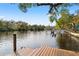 Scenic waterfront view with a wooden dock, lush greenery, and a calm river perfect for boating at 906 W Henry Ave, Tampa, FL 33604