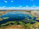 Beautiful aerial view showcasing a vast lake with lush vegetation and clear blue skies at 9804 Rowing Dale Bnd, Wesley Chapel, FL 33545