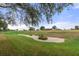 Scenic view of a golf course featuring green grass, trees, and a sand trap at 11121 Sun Tree Rd, Hudson, FL 34667