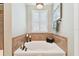 Bright bathroom featuring a soaking tub with tile surround, plantation shutters, and stylish decor at 11132 Roseate Dr, Tampa, FL 33626