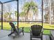 Enjoy the lake view from this screened porch with wooden chairs at 16320 Rock Lake Dr, Odessa, FL 33556