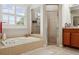 Bright bathroom features a tub under a window, walk-in shower, and wood vanity at 1642 Daylily Dr, Trinity, FL 34655