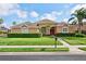 Charming single-story home with manicured lawn, mature landscaping, and a welcoming red front door at 1642 Daylily Dr, Trinity, FL 34655