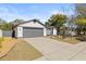 Front view of a house with a gray garage door and landscaping at 1741 Spinning Wheel Dr, Lutz, FL 33559