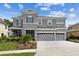 Two-story house with gray siding, three car garage, and neatly landscaped yard at 19322 Autumn Chase Ct, Land O Lakes, FL 34638