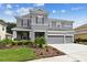 Two-story house with gray siding, three car garage, and manicured lawn at 19322 Autumn Chase Ct, Land O Lakes, FL 34638