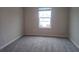 Well-lit bedroom with grey carpet and window looking out to houses at 19639 Shady Oak Dr, Land O Lakes, FL 34638