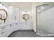 Bright bathroom featuring double vanities with round mirrors, white cabinets and a glass enclosed shower at 2186 Coffee Pot Ne Blvd, St Petersburg, FL 33704