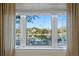 Scenic view of a lake framed by a multi-pane window and elegant drapery. Serene and inviting at 2186 Coffee Pot Ne Blvd, St Petersburg, FL 33704