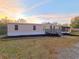 A beige manufactured home with a gray deck, landscaping, and screened porch at 3749 Loury Dr, Wesley Chapel, FL 33543