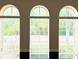 Three arched windows with blinds, offering natural light and backyard views at 4110 Huntingdale Ct, Wesley Chapel, FL 33543