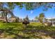 Expansive backyard featuring lush lawn, mature trees, a unique buffalo statue and waterfront views at 521 Harbor N Dr, Indian Rocks Beach, FL 33785