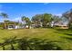 Spacious backyard featuring a lush green lawn, palm trees, and glimpses of nearby homes at 521 Harbor N Dr, Indian Rocks Beach, FL 33785