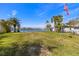 Large waterfront backyard with lush grass, palm trees, and an American flag waving in the breeze at 521 Harbor N Dr, Indian Rocks Beach, FL 33785