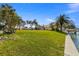 Sprawling backyard with green lawn, mature palm trees and a waterfront dock at 521 Harbor N Dr, Indian Rocks Beach, FL 33785