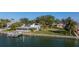 Waterfront home featuring a private dock, screened in lanai, and lush tropical landscaping on a sunny day at 521 Harbor N Dr, Indian Rocks Beach, FL 33785