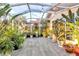 Relaxing screened patio with tile flooring, string lights, and lush tropical plants at 5232 White Sand Ne Cir, St Petersburg, FL 33703