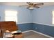 Bedroom featuring blue walls, carpet, and ceiling fan with a view into two windows at 5353 Shaw St, New Port Richey, FL 34652