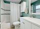 Bright bathroom with a shower-tub combo, white vanity, medicine cabinet, and blue-green accent wall at 6702 Harbor Dr, Hudson, FL 34667