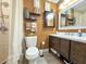 Bathroom featuring a tiled walk-in shower, toilet, dark wood vanity, and decorative shelves at 6702 Harbor Dr, Hudson, FL 34667