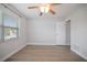 An empty bedroom featuring a ceiling fan, window with blinds, and a closed white door at 6702 Harbor Dr, Hudson, FL 34667