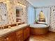 Elegant bathroom featuring double sinks, a large soaking tub, and wood cabinets at 8326 Fantasia Park Way, Riverview, FL 33578