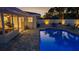 A beautifully lit backyard featuring a pool, outdoor seating, and well-manicured landscaping at 4523 Clearwater Harbor S Dr, Largo, FL 33770