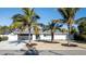 Charming home with modern curb appeal, a gray driveway, and tropical landscaping with palm trees at 4523 Clearwater Harbor S Dr, Largo, FL 33770
