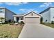Tan one-story house with a two-car garage and landscaped yard at 5322 Fiddle Fig Ave, Wimauma, FL 33598