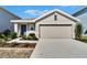 Beige house with gray door, two-car garage, and landscaped yard at 5322 Fiddle Fig Ave, Wimauma, FL 33598