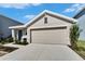 Newly built beige house with gray door and two-car garage at 5322 Fiddle Fig Ave, Wimauma, FL 33598