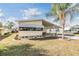Charming home exterior with a carport, well-manicured lawn, and a palm tree at 5539 Regal Way, Zephyrhills, FL 33541