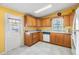 Bright kitchen with wood cabinets, white appliances, and an access door at 5539 Regal Way, Zephyrhills, FL 33541