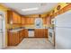 Well-lit kitchen features wood cabinetry, white appliances, and tile flooring at 5539 Regal Way, Zephyrhills, FL 33541