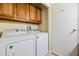 Functional laundry room with a washer, dryer, tile flooring and overhead storage cabinets at 5539 Regal Way, Zephyrhills, FL 33541