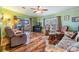 Bright living room with hardwood floors, comfortable seating, ceiling fan, and a fireplace at 5539 Regal Way, Zephyrhills, FL 33541