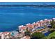 Aerial view of a waterfront condominium complex boasting red tile roofs, lush greenery, and a sparkling pool with water views at 5633 Puerta Del Sol S Blvd # 306, St Petersburg, FL 33715