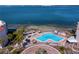 Aerial view of a pool and waterfront area surrounded by palm trees, tiki umbrellas and lounge chairs at 5633 Puerta Del Sol S Blvd # 306, St Petersburg, FL 33715