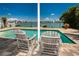 Relaxing poolside view with wooden chairs and water view at 817 Bay Point Dr, Madeira Beach, FL 33708