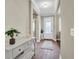 Bright foyer with white console table, decorative vase, and wood-look flooring leading into the home at 12099 Gavin Ln, Odessa, FL 33556