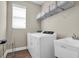 Functional laundry room with modern washer and dryer, sink, and storage shelf, plus a window at 12099 Gavin Ln, Odessa, FL 33556