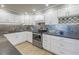 Contemporary kitchen featuring white cabinets, mosaic backsplash, granite countertops, and stainless steel appliances at 220 Belleview Blvd # 108, Belleair, FL 33756