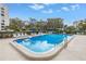 Community pool with ledge and metal hand railing, with blue umbrellas and lounge seating at 220 Belleview Blvd # 108, Belleair, FL 33756