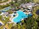 Aerial view of a community pool with lounge chairs, tropical landscaping, and tennis courts at 301 Andover S Pl # 185, Sun City Center, FL 33573