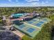 Aerial view featuring pickleball courts with players, pool, lake, and surrounding trees at 301 Andover S Pl # 185, Sun City Center, FL 33573