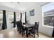 Bright dining room with a large window with drapes, modern light fixture, and seating for six at 4927 Rolling Green Dr, Wesley Chapel, FL 33543