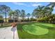 Backyard putting green on a manicured lawn, complemented by elegant stonework and landscaping at 633 Poinsettia Rd, Belleair, FL 33756